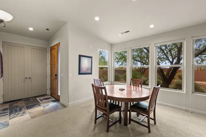Recessed lighting throughout, wood-paneled entry door, slate tile entry flooring, multiple windows, and light-colored carpeting