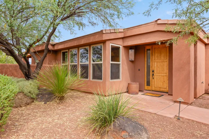 Stucco exterior with a tile roof, featuring a wood-finish entry door with a sidelight, and a large window bank