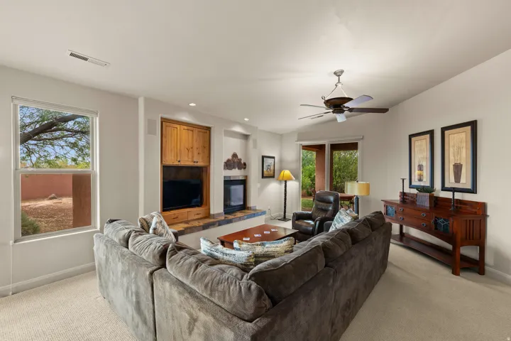 Built-in entertainment center with wood cabinetry, integrated fireplace, ceiling fan, carpet flooring, and sliding glass door