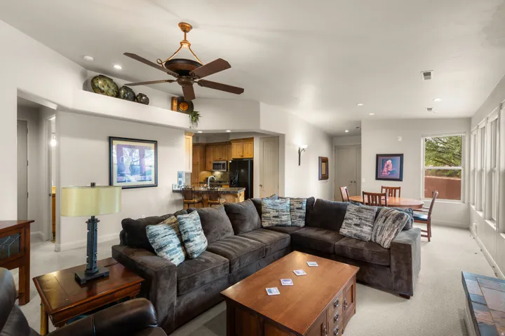Open-concept living space featuring a ceiling fan, recessed lighting, expansive windows, and an adjacent kitchen with wood cabinetry