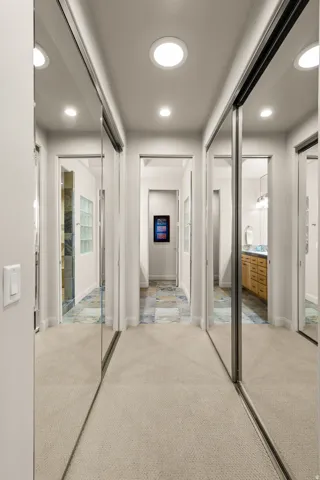 Hallway featuring flush-mounted ceiling lights, carpeted flooring, and mirrored closet doors