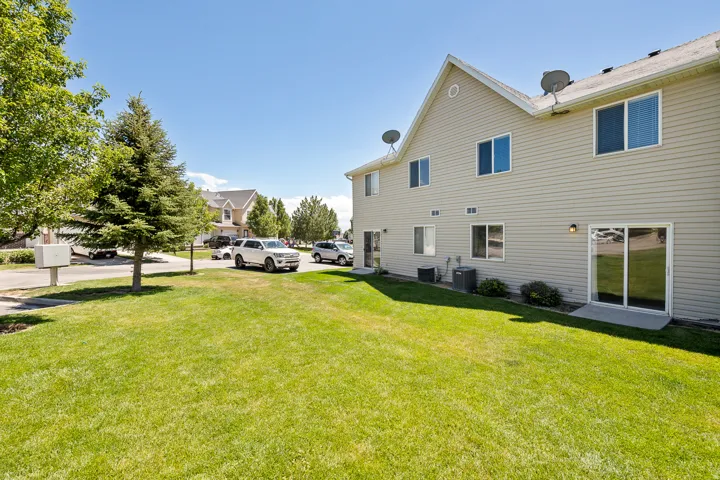 Vinyl siding exterior with multiple windows, two sliding glass doors, and a well-maintained lawn