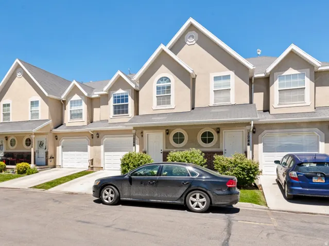 Stucco exterior with gabled roofline, arched and circular windows, attached garages, and concrete driveways
