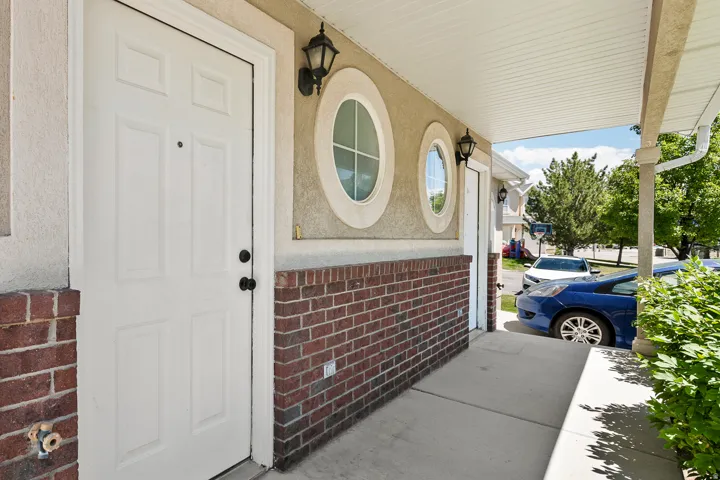 Entryway featuring a paneled door with black hardware, brick wainscoting, two oval windows, and exterior light fixtures