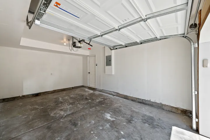 Attached garage featuring concrete flooring, an automatic garage door opener, and a side access door