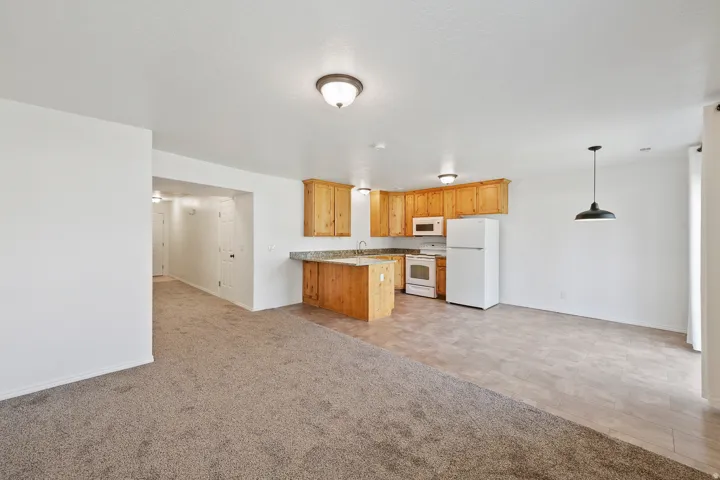 Kitchen featuring wood cabinetry, white appliances, and a breakfast bar