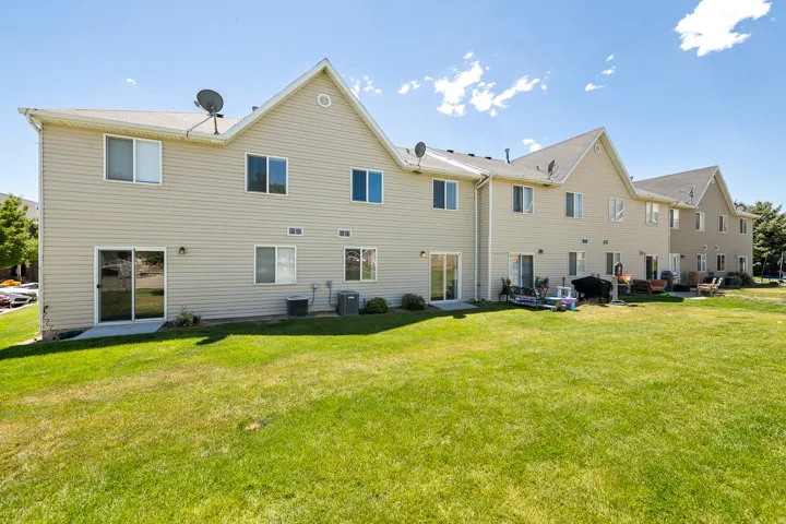 Light-colored siding exterior, multiple sliding glass patio doors, gable rooflines, and a grassy outdoor area