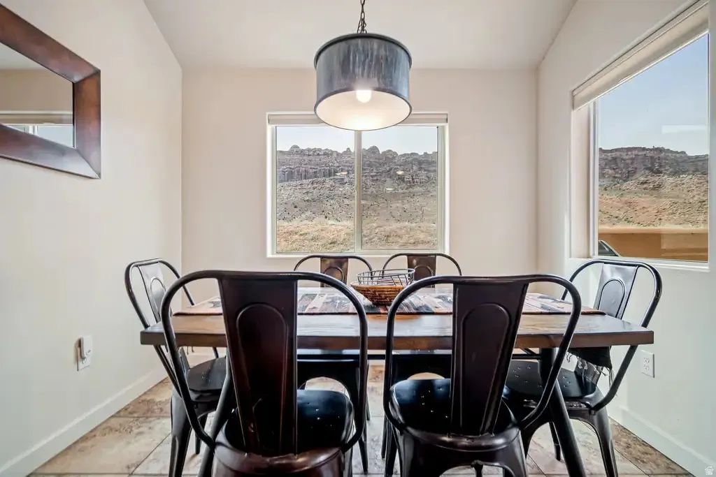 Two windows with roller shades, a rustic wood-finish table, and tile flooring