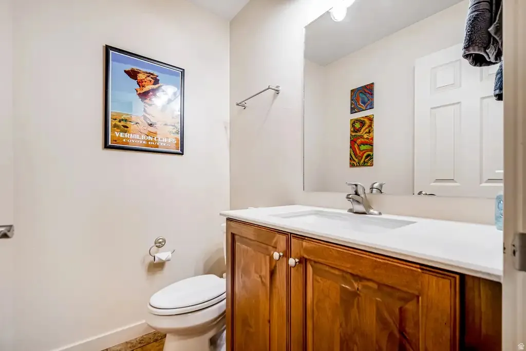 Wood-finish vanity with a white countertop and integrated sink, complemented by a chrome faucet and a large wall-mounted mirror