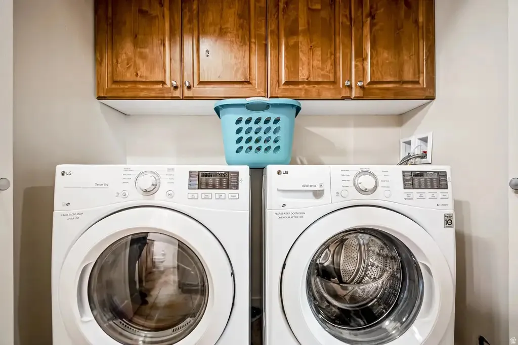 Laundry area featuring wood-finish cabinetry and white front-load appliances