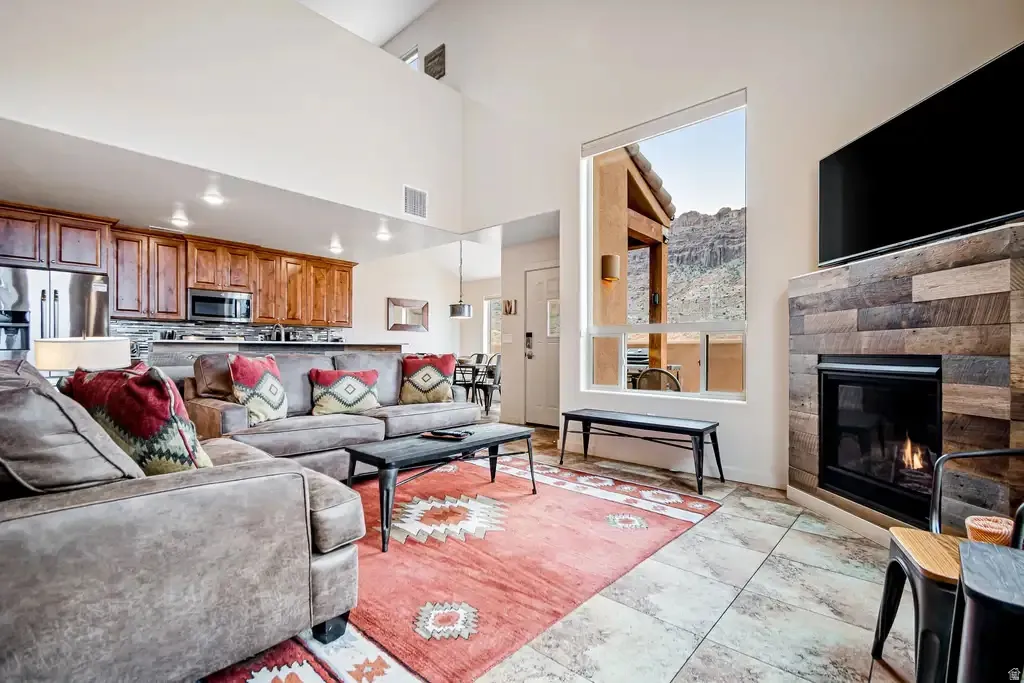 Vaulted ceilings with recessed lighting, a stone-clad fireplace, and a large picture window
