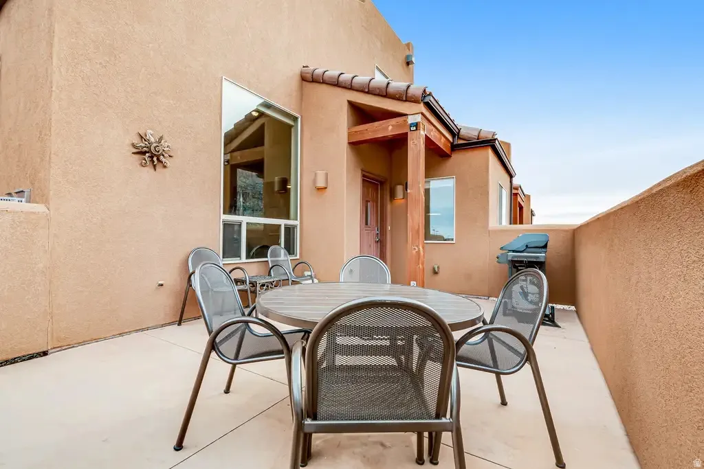 Exterior patio with textured stucco walls, an angled large window, and a covered entry