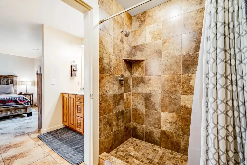 Tiled shower stall with a built-in niche, mosaic tile floor, and a polished chrome showerhead