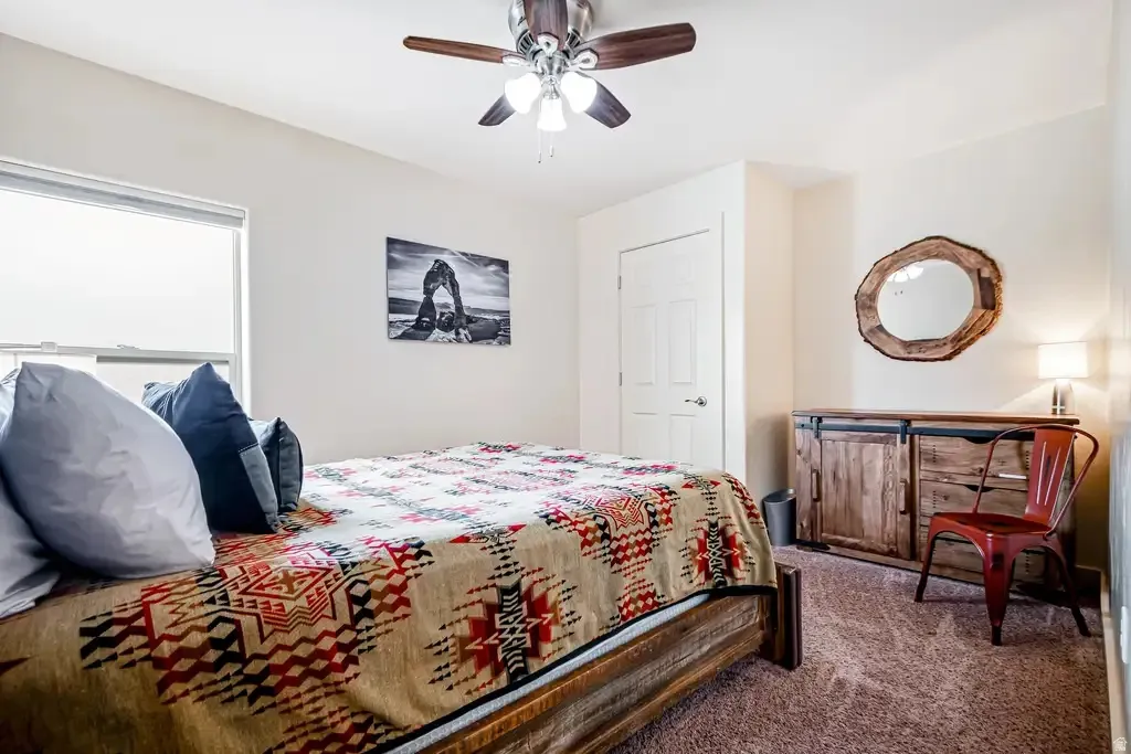 Wall-mounted ceiling fan, wood-finish bed frame, light-toned walls, and a window with blinds