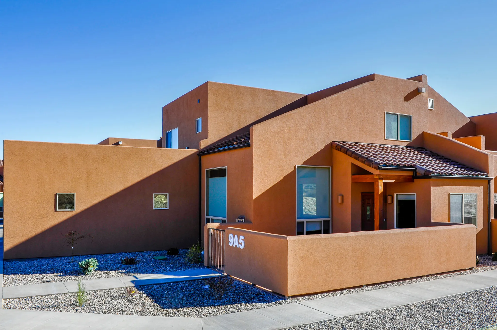Stucco exterior with a tiled entry roof and integrated privacy wall