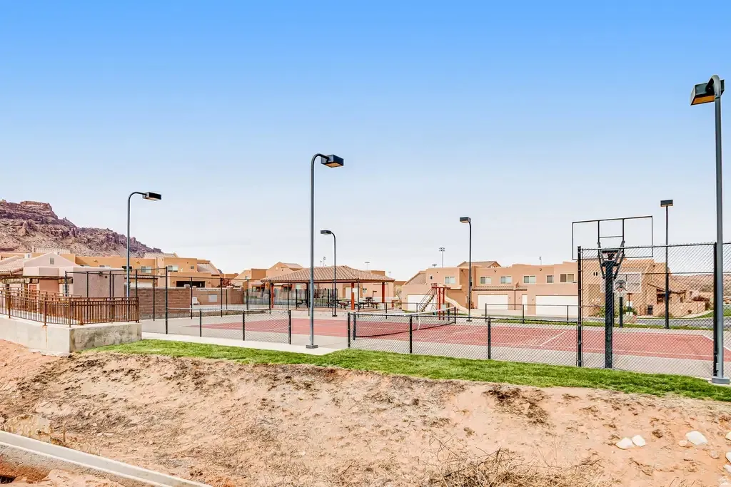 Sports court with a basketball hoop, tennis court, and perimeter fencing