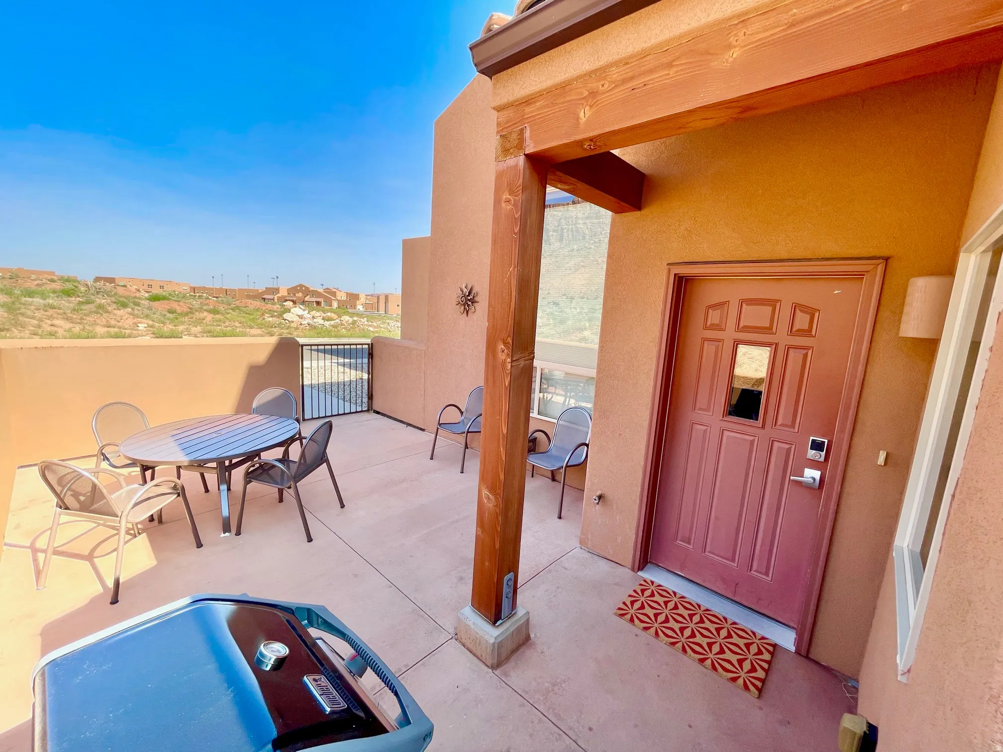 Private outdoor patio with a concrete surface, featuring a security gate and a stucco exterior