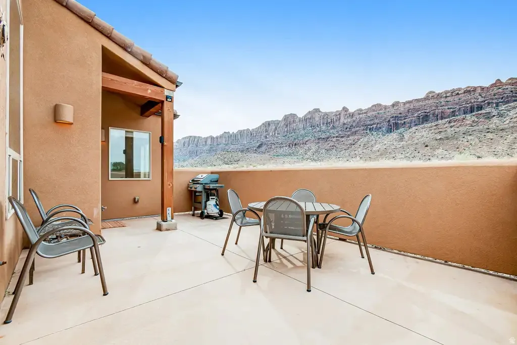 Expansive outdoor patio with a stucco exterior, concrete flooring, and an integrated wood-beam overhang