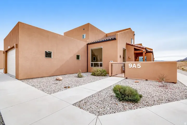 Stucco exterior with a tiled entry roof, integrated garage, and a gated private courtyard