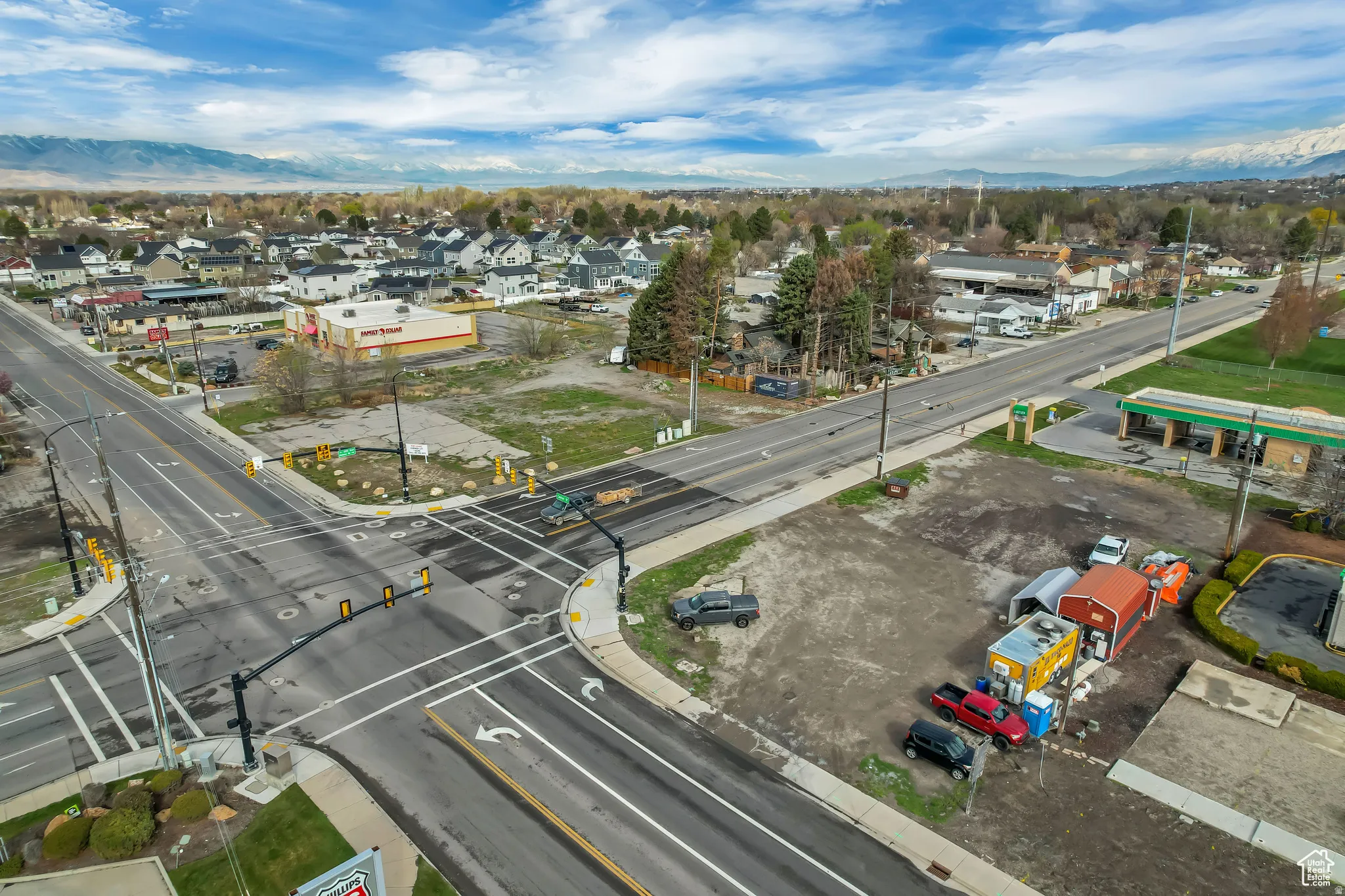 Road intersection with clearly marked lanes, surrounding commercial buildings, and distant mountain ranges