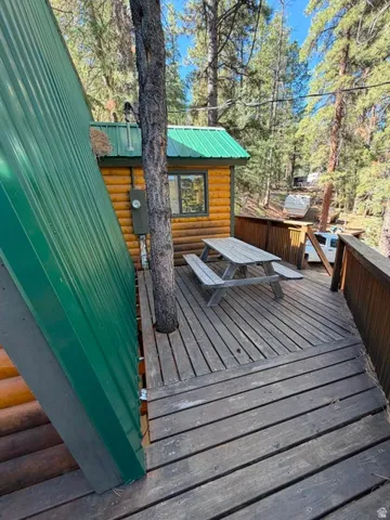 Expansive wood deck with plank flooring, featuring a built-in tree and a rustic picnic table