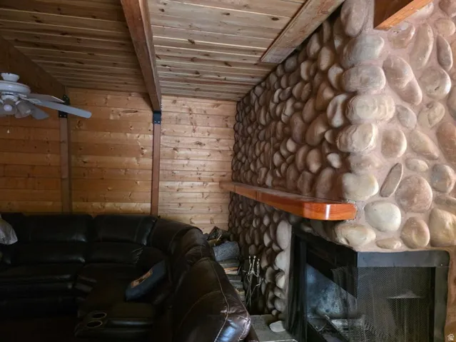 Stone fireplace with a wood mantel, wood-paneled walls, and a wood plank ceiling