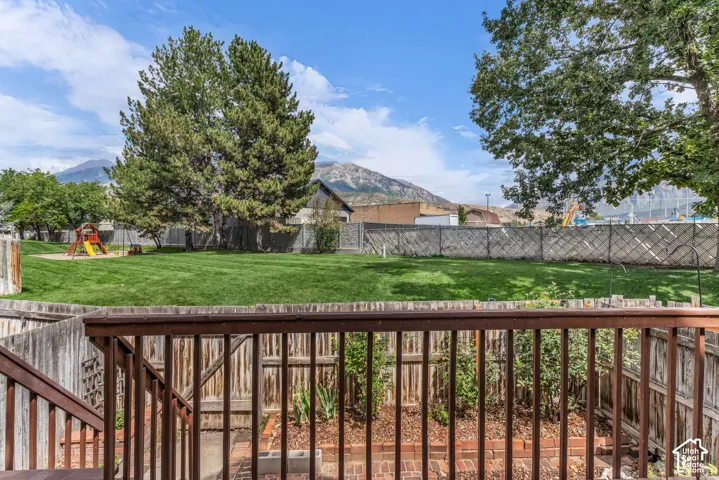 Expansive backyard with a manicured lawn, established trees, and playground