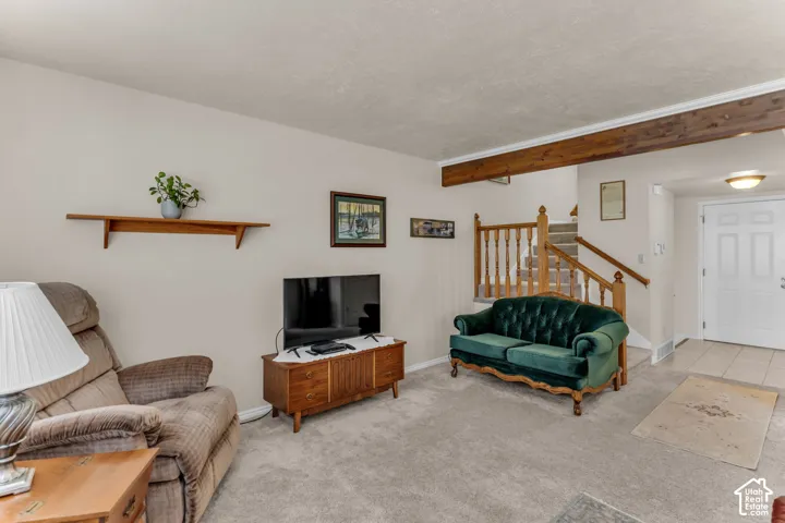 Carpeted living area with a visible staircase featuring wood railings