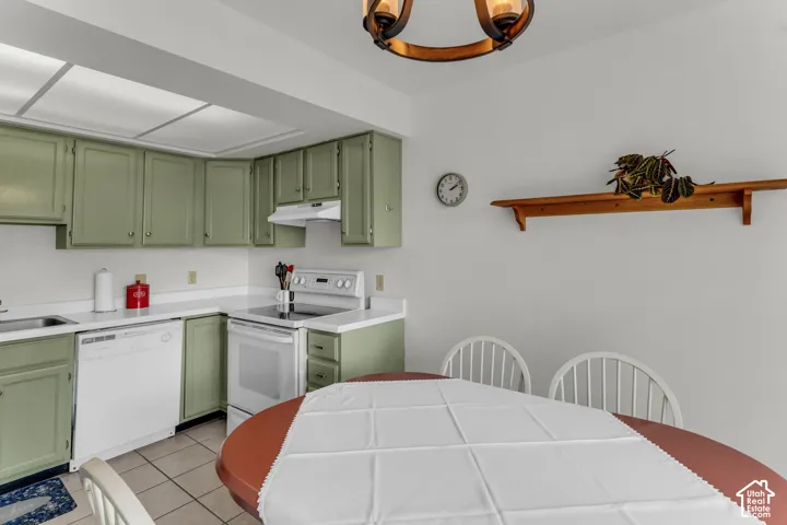 Kitchen featuring green cabinetry, white countertops, built-in dishwasher, and white electric range with overhead ventilation