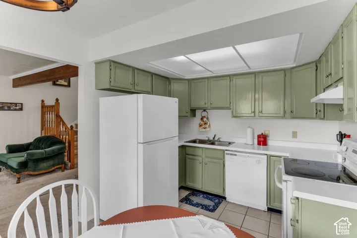 Kitchen featuring ample cabinetry, white appliances, dual basin sink, white countertops, and tile flooring