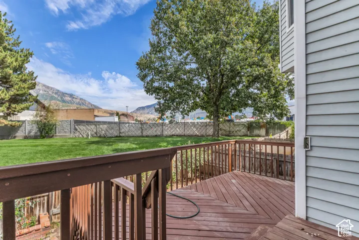 Wood-finish deck with railing, light blue siding, and expansive grassy yard