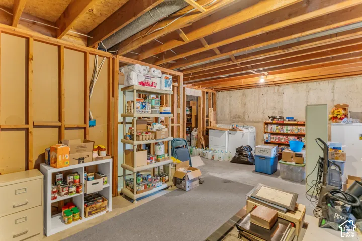 Unfinished basement with exposed wood framing, concrete foundation walls, and a visible wood-beamed ceiling