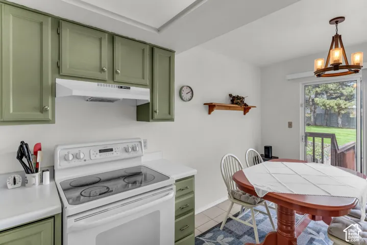 Green cabinetry, white countertops, built-in range, pendant light fixture, and glass sliding door