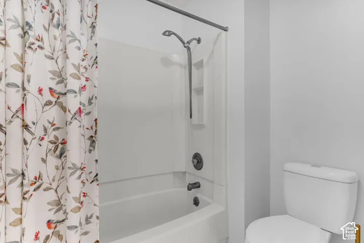 White integrated shower/tub unit with dark-finish fixtures and a shower niche