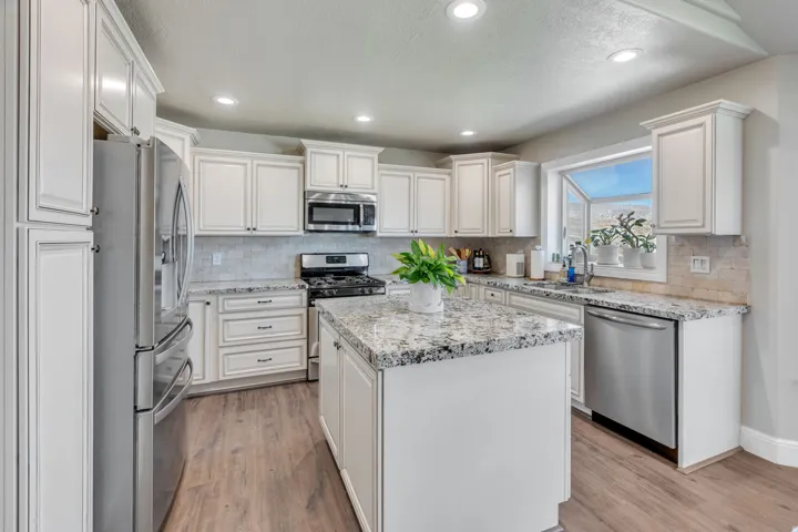 Kitchen featuring white cabinetry, granite countertops, stainless steel appliances, wood-finish flooring, and recessed lighting