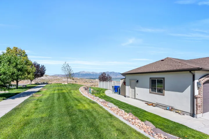 Exterior stucco finish, attached garage with arched brick detailing, asphalt shingle roofing, and a concrete driveway