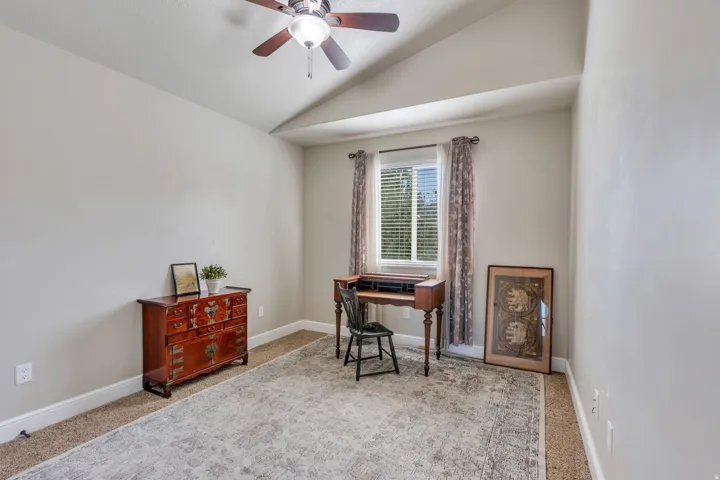 Vaulted ceiling with a ceiling fan and light fixture, window with blinds and drapes, and carpeted flooring
