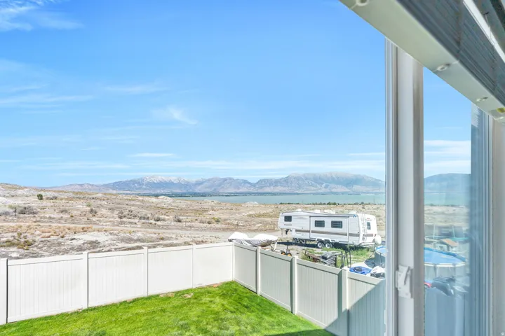 Expansive desert landscape with distant mountains, a body of water, and a vibrant green lawn