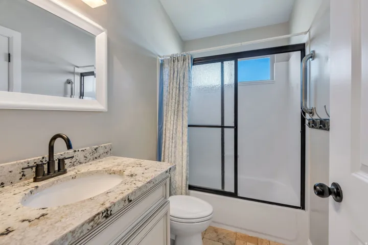 Vanity featuring a stone countertop, an undermount sink, and a dark-finish faucet