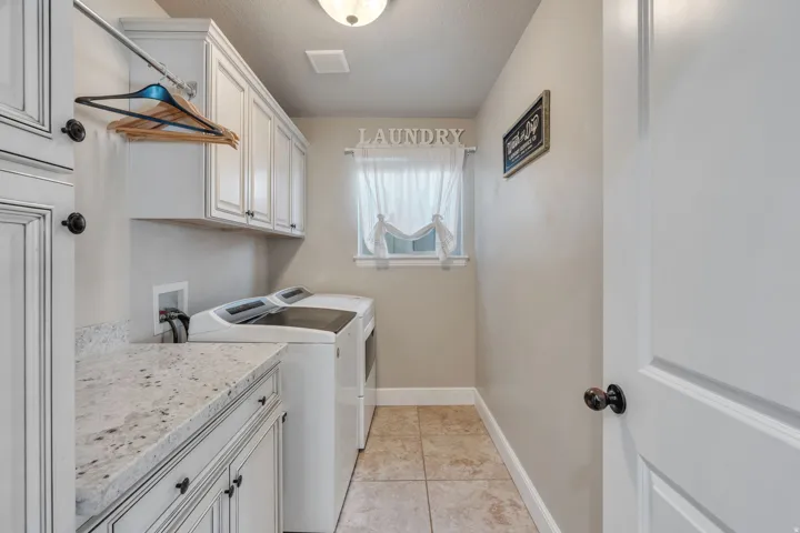 Built-in cabinetry with dark hardware, stone-finish countertop, tiled flooring, and a window with natural light