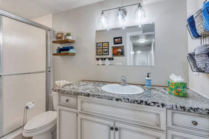 Vanity with a built-in sink, stone-finish countertop, white cabinetry, and wall-mounted light fixture