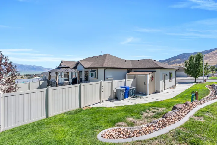 Expansive backyard featuring a manicured lawn, established landscaping, and a permanent gazebo structure