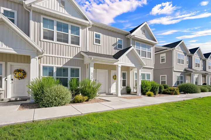 Townhome exterior featuring board and batten siding, white-trimmed windows, a covered entry, and a concrete walkway