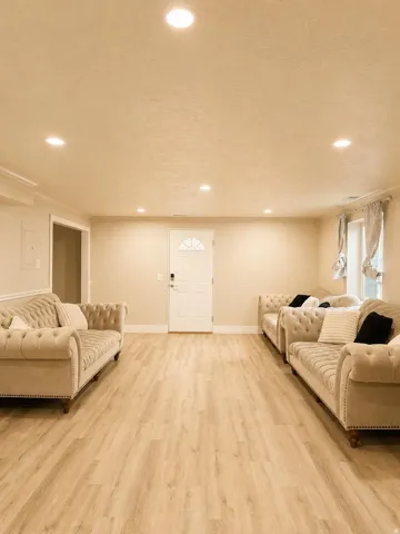Recessed lighting illuminates the spacious room with wood-finish flooring
