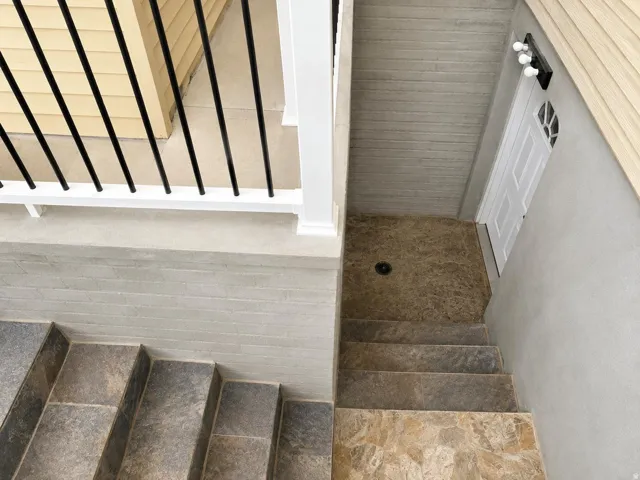 Exterior access featuring tiled steps, a white paneled door with glass inserts, and a three-light fixture