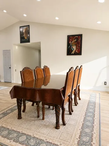 Vaulted ceiling with recessed lighting, light wood-finish flooring, and a paneled interior door