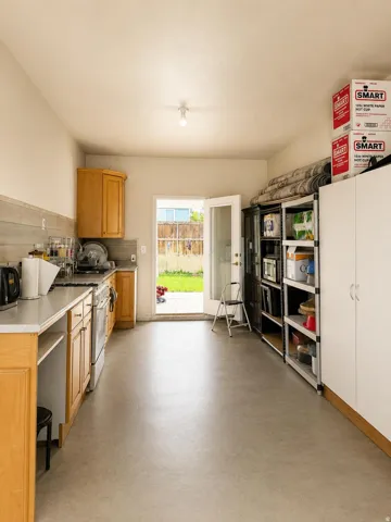 Light wood-finish cabinetry with silver hardware, gray subway tile backsplash, light countertop, stainless steel oven, and light gray flooring
