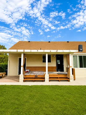Backyard patio with pergola, built-in benches, and a grass lawn