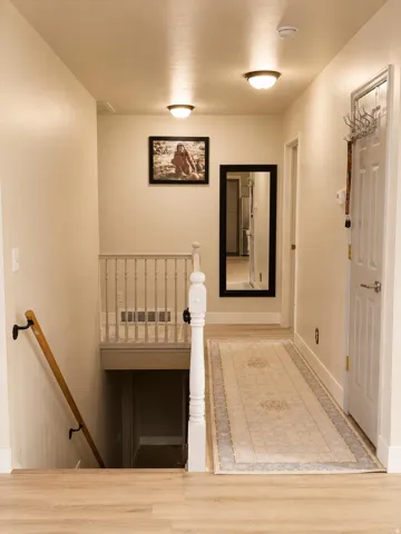 Wood-finish flooring with a white spindle railing and a wood handrail
