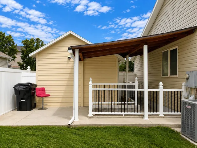 Covered patio featuring a wood-finish ceiling, white railing with black balusters, and a concrete slab